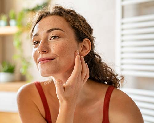 Young Woman Mirror | Northeast Medical Aesthetics | Beauty & Ant-Aging Services